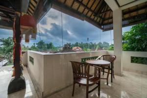 balcón con mesa y sillas y ventana grande en Bangbang Guest House Ubud, en Ubud