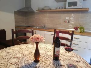 a table with a bottle of wine and a flower on it at Apartments Rogac in Rogač