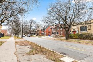 an empty street in a residential neighborhood with houses at Stately Studio Apartment in Detroit