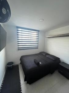 1 dormitorio con cama negra y ventana en Habitación Auxiliar en Apto Compartido piso 26, en Bucaramanga