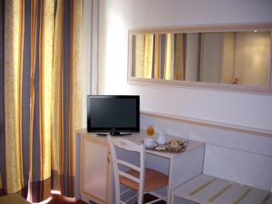 a room with a desk with a television and a chair at Hotel Adler in Milan