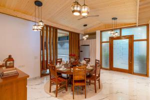 カソーリにあるStayVista at Aykon Estate - Modern Interiors, Viewsのテーブルと椅子と窓のあるダイニングルーム