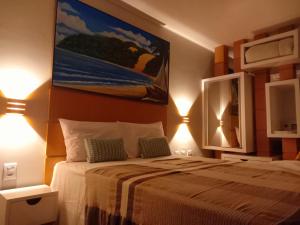 um quarto com uma cama com dois candeeiros e uma pintura na parede em Ilusion Flats Aconchego de Ponta Negra em Natal