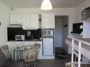 uma cozinha com uma mesa e uma cozinha com armários brancos em Studio Chamrousse, 1 pièce, 3 personnes - FR-1-340-264 em Chamrousse