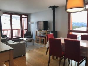 salon ze stołem, krzesłami i telewizorem w obiekcie Appartement spacieux avec parking, balcon et accès piscine - Front de neige - FR-1-346-536 w mieście Arc 1800