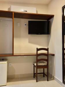 una camera con sedia e televisore appeso a un muro di Pousada OCEAN a Saquarema