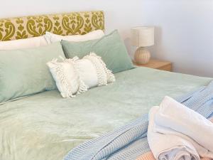 ein Bett mit grüner Bettwäsche und Kissen darauf in der Unterkunft ocean view 2 Bedrooms at Broadbeach in Gold Coast + 3 Fotos