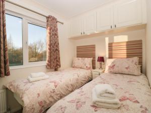 a bedroom with two beds and a window at Bramley Lodge in Puxton
