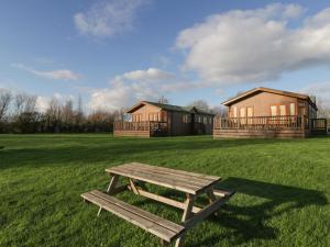 a picnic table in a field with houses in the background at Bramley Lodge in Puxton