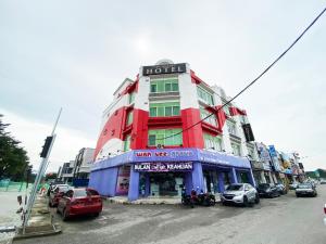 a red and white building with cars parked on a street at D'concept Hotel Kulim in Kulim