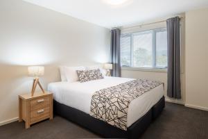 Un dormitorio con una cama grande y una ventana en Warners Bay Apartments, en Warners Bay