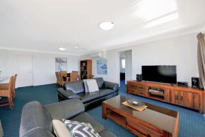 ein Wohnzimmer mit einem Sofa und einem Flachbild-TV in der Unterkunft 404a Coral Sands in Bargara