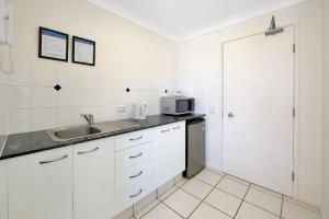 a white kitchen with a sink and a microwave at 404b Coral Sands in Bargara