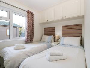2 Betten in einem Zimmer mit 2 Fenstern in der Unterkunft Blenheim Lodge in Puxton
