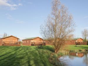 eine Gruppe von Häusern auf einem Feld mit einem Teich in der Unterkunft Blenheim Lodge in Puxton