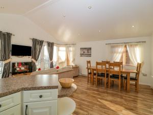 eine Küche und ein Wohnzimmer mit einem Tisch und Stühlen in der Unterkunft Harvester Lodge in Puxton