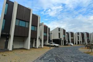 a row of buildings with a car parked in front at Coveted Palms Village Pension in Jeju