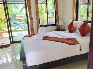 a bedroom with a bed with white sheets and red pillows at Palm Tian Homes A17 in Ban Chong Phli