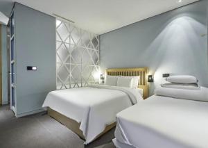 two beds in a hotel room with white sheets at Hotel The Designers Jongro in Seoul