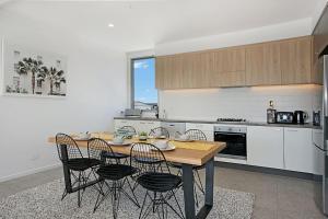 uma cozinha com uma mesa de madeira e algumas cadeiras em Ocean Terrace em Kingscliff