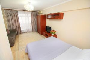 Schlafzimmer mit einem weißen Bett und einem TV in der Unterkunft АРБАТ отличная 1 комнатная, Абылай хана 74 in Almaty