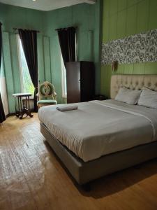 um quarto com uma cama grande e uma cadeira em Mojokerto Classic Homestay em Mojokerto