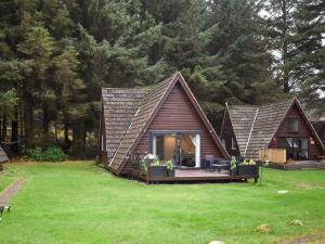 a house with a pitched roof on a green lawn at Pine Needle Lodge in Kilfinnan
