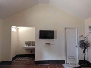 een kamer met een witte muur en een tv. bij Miguel's Homestay in Pañge