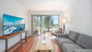 a living room with a couch and a large screen tv at Seaspray 2 in Yamba
