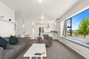 ein Wohnzimmer mit einem Sofa und einem Tisch in der Unterkunft Garden Grove Gem - Lake Taupō Holiday Home in Taupo