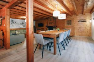 een eetkamer met een houten tafel en stoelen bij 2AlpesChalets - Chalet Marie 1 - Standing et Sauna aux pieds des pistes in Les Deux Alpes