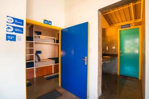 a room with a blue door and a room with a bed at Shalom Backpackers Anjuna Goa in Anjuna
