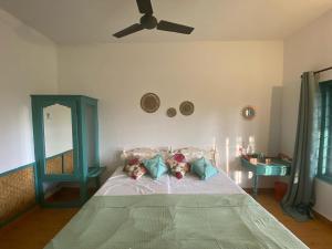 Petit Ana Beach Retreat في فاركَالا: غرفة نوم مع سرير ومروحة سقف