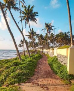 una strada sterrata accanto alla spiaggia con palme di Petit Ana Beach Retreat a Varkala