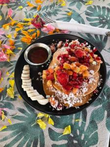 a plate of pancakes with fruit on a table at Petit Ana Beach Retreat in Varkala