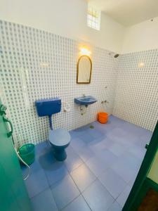 een badkamer met een blauw toilet en een wastafel bij Petit Ana Beach Retreat in Varkala