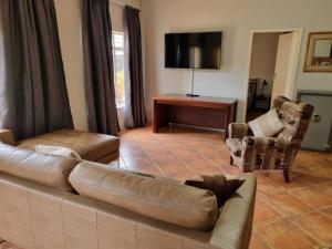 a living room with a brown leather couch and chairs at Pecan Nut Place in Dalmada AH