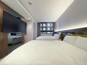 Habitación de hotel con 2 camas y TV de pantalla plana. en CHECK inn Taichung Qinghai en Taichung