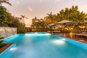 ein großer blauer Pool mit Tischen und Sonnenschirmen in der Unterkunft The Billi Resort in Broome