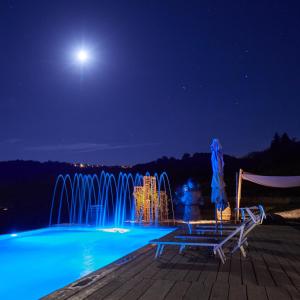 ein Pool mit einem Brunnen in der Nacht mit dem Mond in der Unterkunft PECORANERA in Bracciano