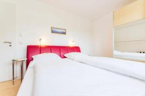 a large white bed with a red headboard in a room at Villa Judith App. 1 Bernstein in Binz