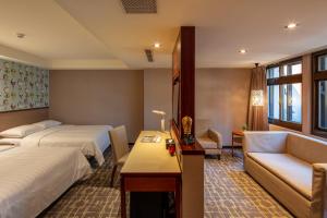 a hotel room with two beds and a couch at Rich & Free Hotel - Kaifeng 富逸旅趣-北車開封館 in Taipei