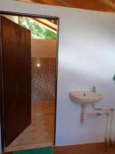 La salle de bains est pourvue d'un lavabo et d'une porte ouverte. dans l'établissement Sing Key Beach, à Masohi