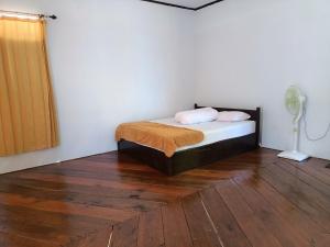 a bedroom with a bed and a fan and wood floors at Sing Key Beach in Masohi