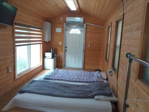 a large bed in a wooden room with a door at Sogobe Cabin in Jeju