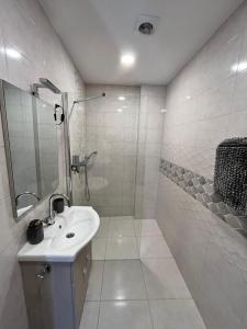 a white bathroom with a sink and a shower at Városi Menedék in Veszprém