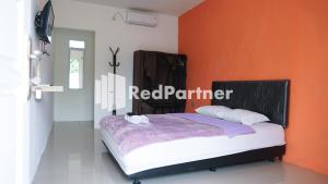 a bedroom with a bed with an orange wall at El Dhiya Syariah Karawaci RedPartner in Tangerang