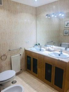 een badkamer met 2 wastafels, een toilet en een spiegel bij Avenida Apartamento in Oviedo