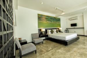 um quarto com uma cama, uma televisão e uma cadeira em Splendour Residence em Balapitiya