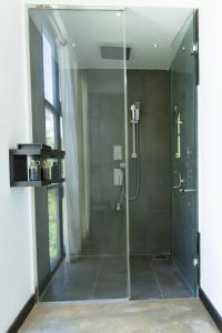 uma casa de banho com um chuveiro e uma porta de vidro em Splendour Residence em Balapitiya